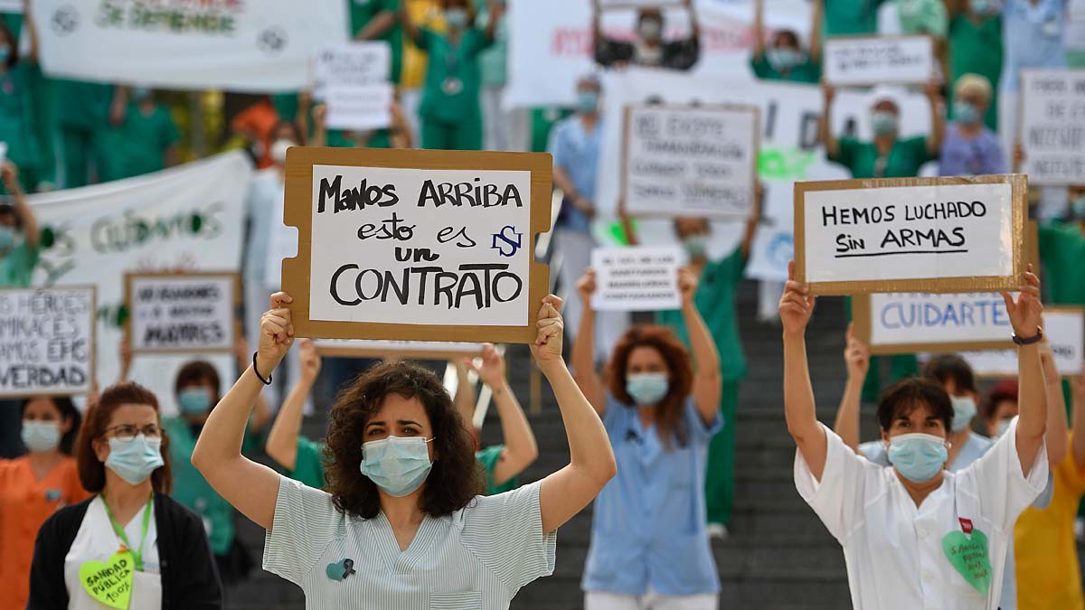 A healthcare worker holds a sign reading "Hands up, this is a contract" during a protest calling for a reinforced healthcare system outside the Gregorio Maranon hospital in Madrid on May 25, 2020 as the country loosens a national lockdown that was put in place to fight the spread of the novel coronavirus. - Spain's government revised downward the country's death toll from the coronavirus by nearly 2,000, bringing the total number of deaths recorded to 26,834. (Photo by PIERRE-PHILIPPE MARCOU / AFP)